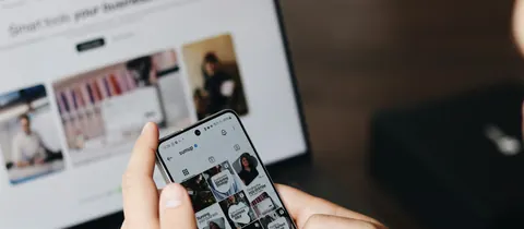Person mit Smartphone vor einem Laptop